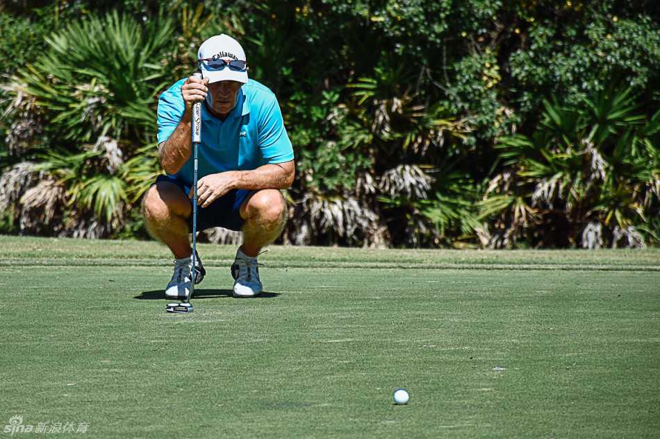 果岭上的激情与友谊 球员在果岭上单膝跪地,全神贯注地观察推杆路线