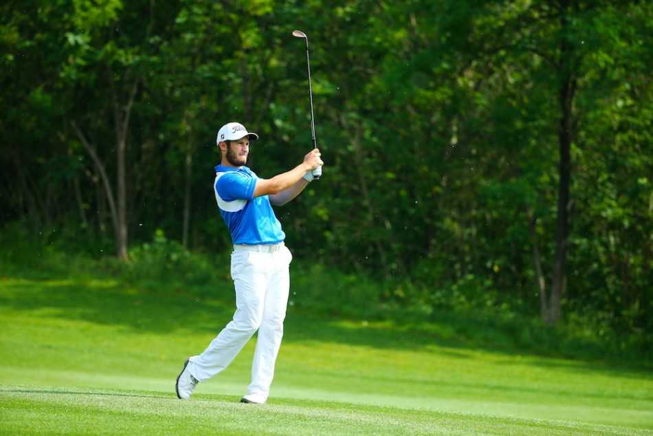 安东尼·布朗深陷沙坑，正挥杆击球，沙粒如金色瀑布般炸起，展现了一次充满力量与技巧的沙坑救球。