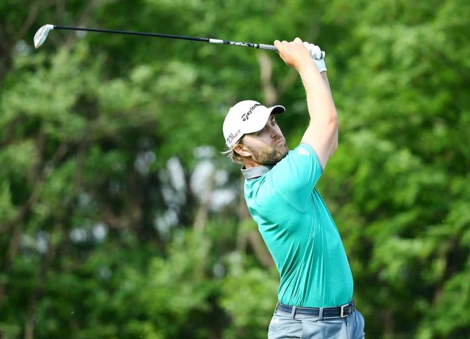 乔恩·马克林正屏息凝神地蹲在果岭上，指尖轻触草面，仔细勘察推杆线路的每一丝起伏。