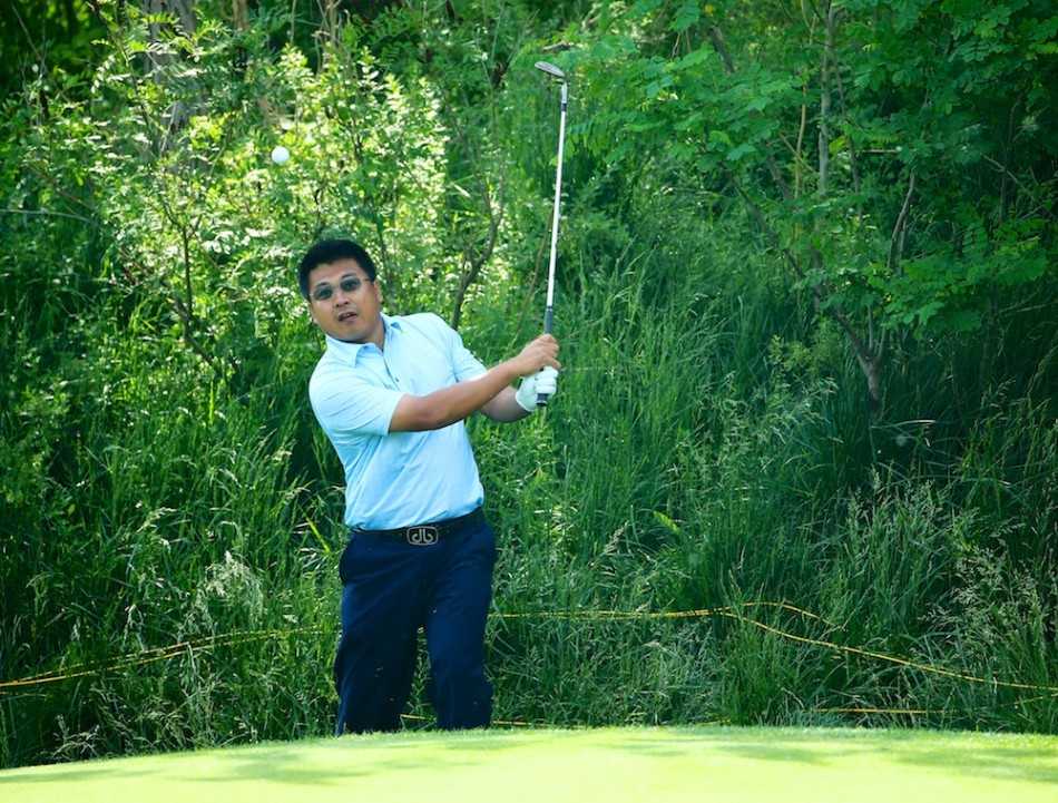 窦泽成在完成击球后从容收杆，身影在辽阔的球场背景下显得沉稳而自信，目光追随着球的飞行轨迹。