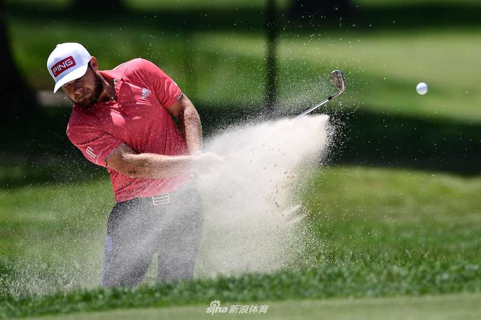 里奇·福勒在沙坑中奋力一击，沙砾飞扬，他正试图从困境中挽回局面，表情专注而投入。
