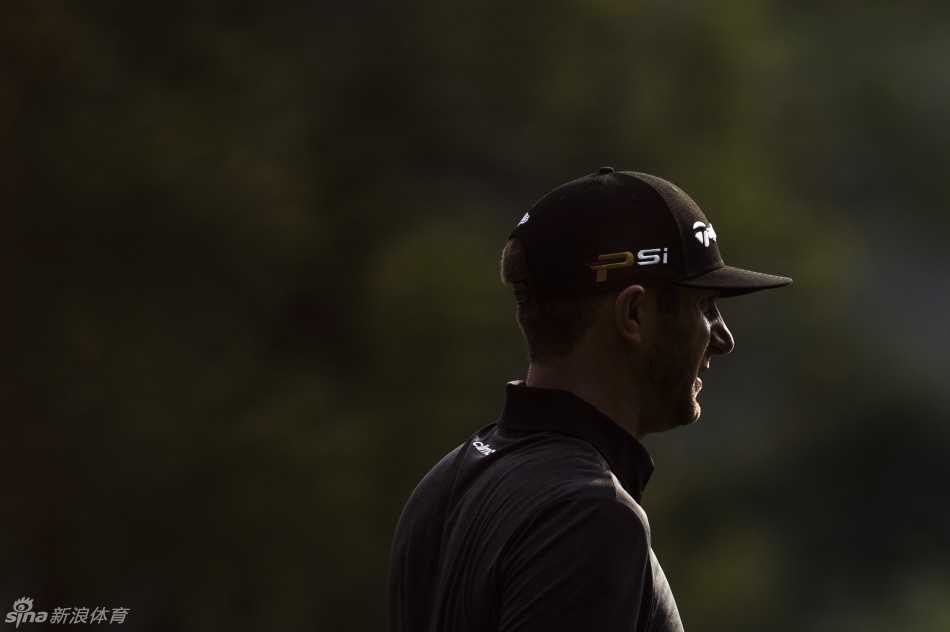 贾斯汀-罗斯在沙坑中屈膝半蹲，全神贯注地执行救球一击，沙粒即将飞溅。