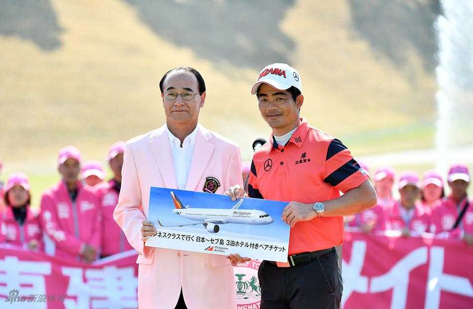 梁文冲推杆瞬间，背景中的记分牌与观众见证着紧张时刻。