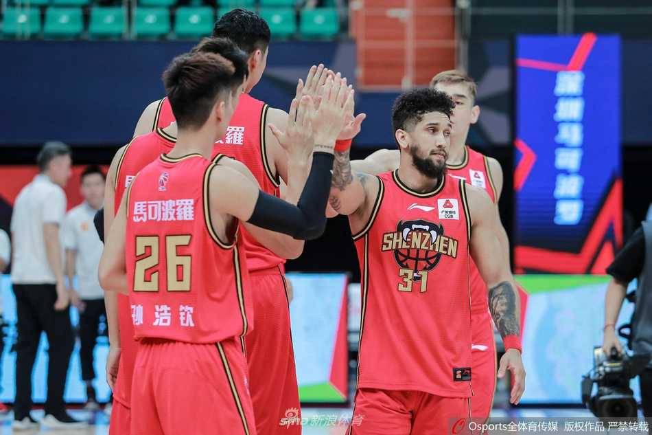 易建联在比赛末段神情轻松地坐在替补席关注场上局势，他的身边围绕着蓄势待发的广东队年轻队员