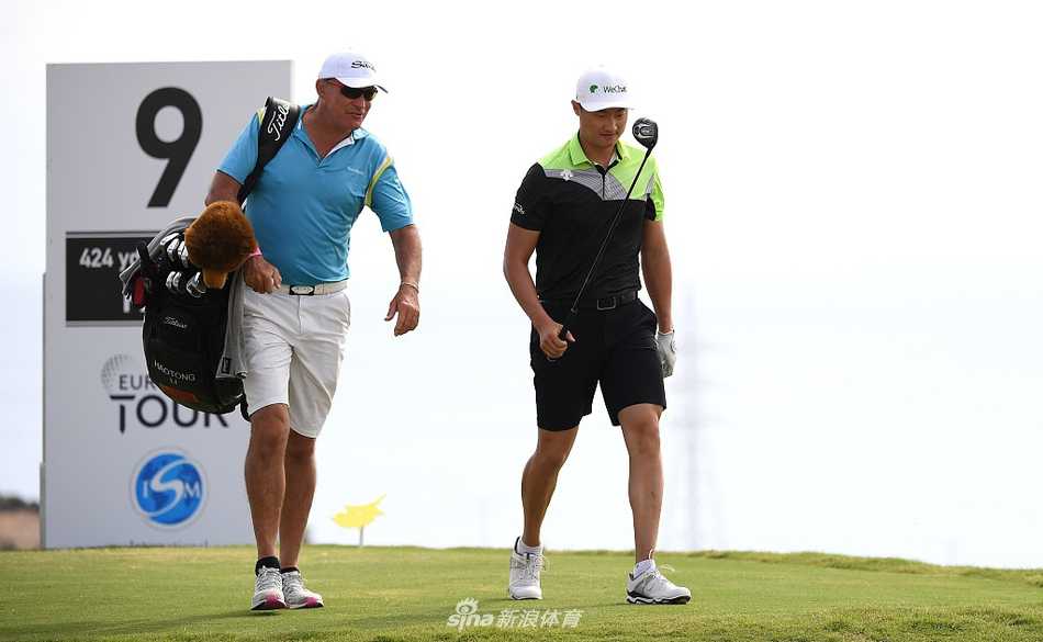 李昊桐凝神注视远方球道，阳光洒在他坚毅的侧脸与挺拔的身姿上，背景是塞浦路斯独特的蓝天与绿茵。