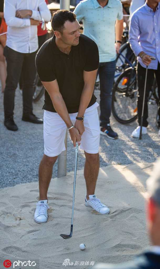 加西亚正微笑着指导一位超模调整推杆姿势，两人专注地看着球洞，画面轻松而有趣。