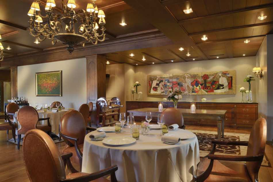 从空中俯瞰酒店建筑群如几颗钻石散落山间，与森林湖泊共同构成和谐生态画卷