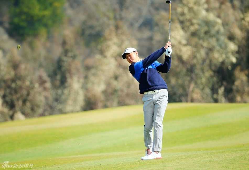 球员金大星在果岭边进行精准的切杆，小球划出优雅弧线飞向球洞