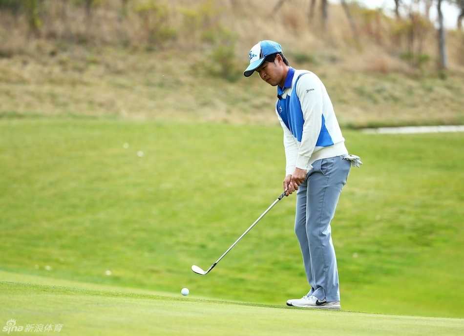 球员罗晓飞推杆后凝神注视，小球在果岭上滚向洞杯的瞬间