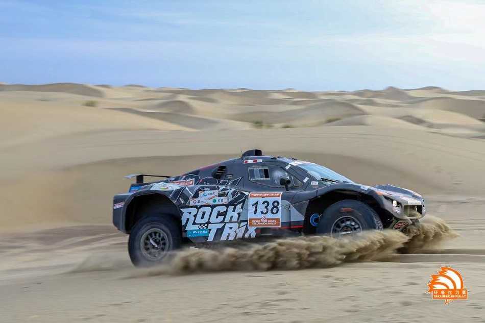 赛车驶过干涸的河床，溅起一片水花与泥浆，在粗犷的背景下绽放出充满野性的动态之美。