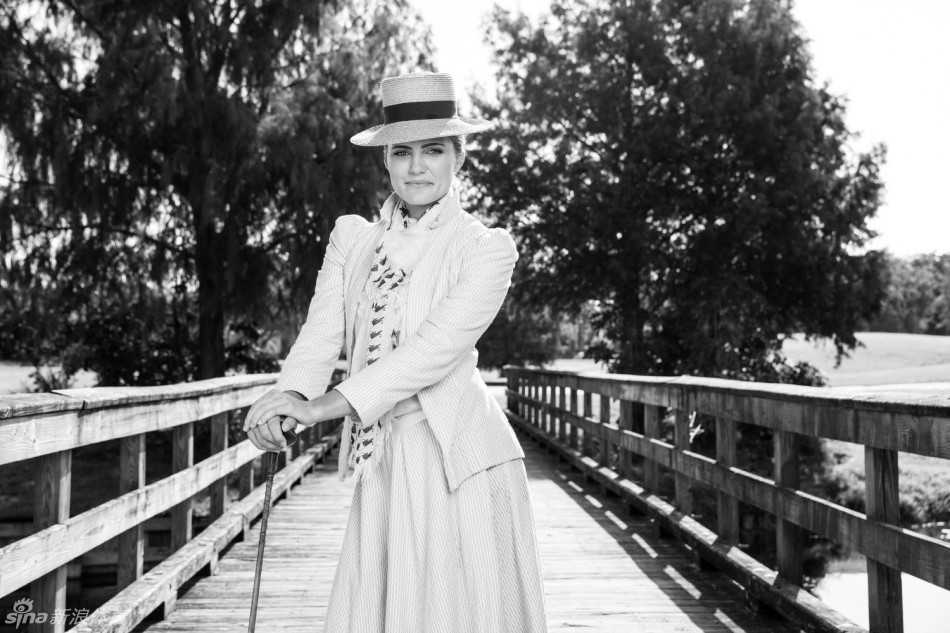 汤普森与身着现代服装的摄影师并肩而立，过去与现在在这一刻形成鲜明对比，突显了这场跨越百年的致敬之旅的非凡意义。