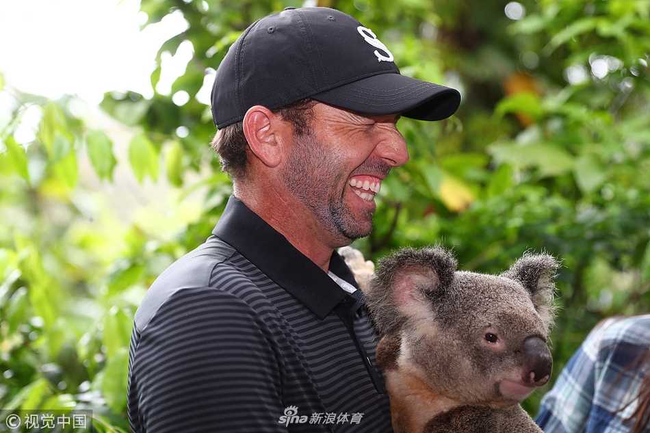 绿茵之外,大师赛冠军加西亚与考拉的温情邂逅 加西亚的娇妻身着优雅长裙,面带温柔笑容,轻轻抚摸怀中温顺考拉的头,仿佛在进行一次亲密的对话。
