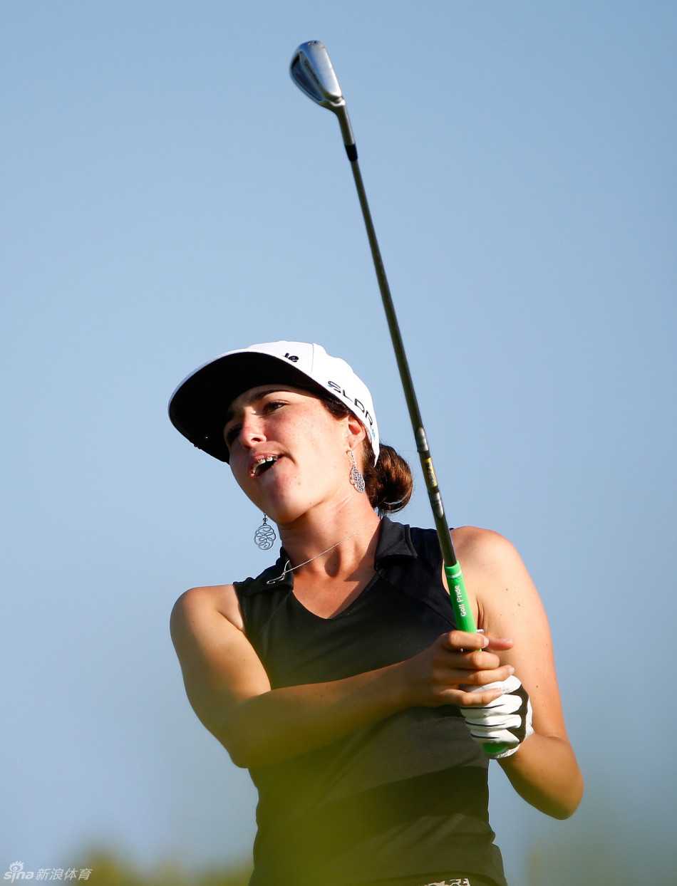 史黛西-路易斯挥杆至顶点的完美姿态，背景的树林与她的身影构成一幅动态油画。