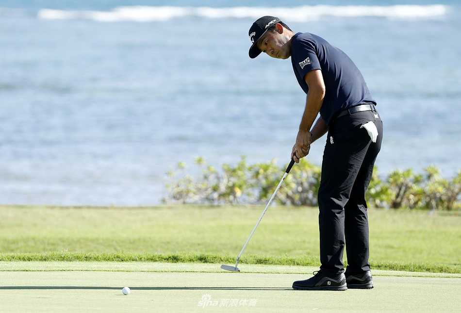 罗相昱在果岭上俯身观察推杆线路，神情专注，夏威夷的微风拂过他的帽檐。