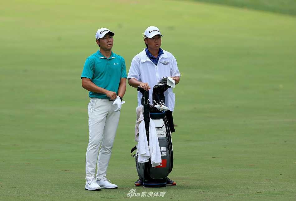 张新军在纪念高球赛决赛轮中专注凝视，缪菲尔德乡村俱乐部的壮丽背景衬托出比赛的庄严气氛。