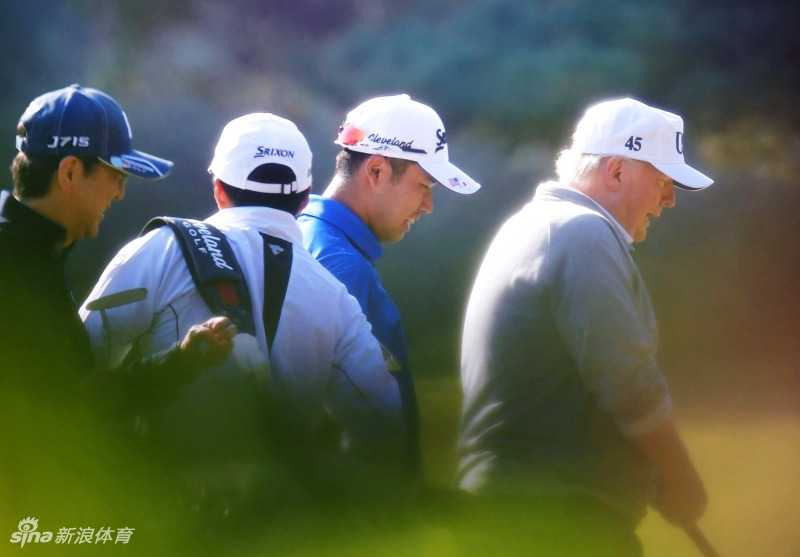 安倍晋三与特朗普并肩行走在高尔夫球场的草地上，两人边走边谈，表情放松，似乎正在进行一场私人交谈，展现了工作之外的人际互动。