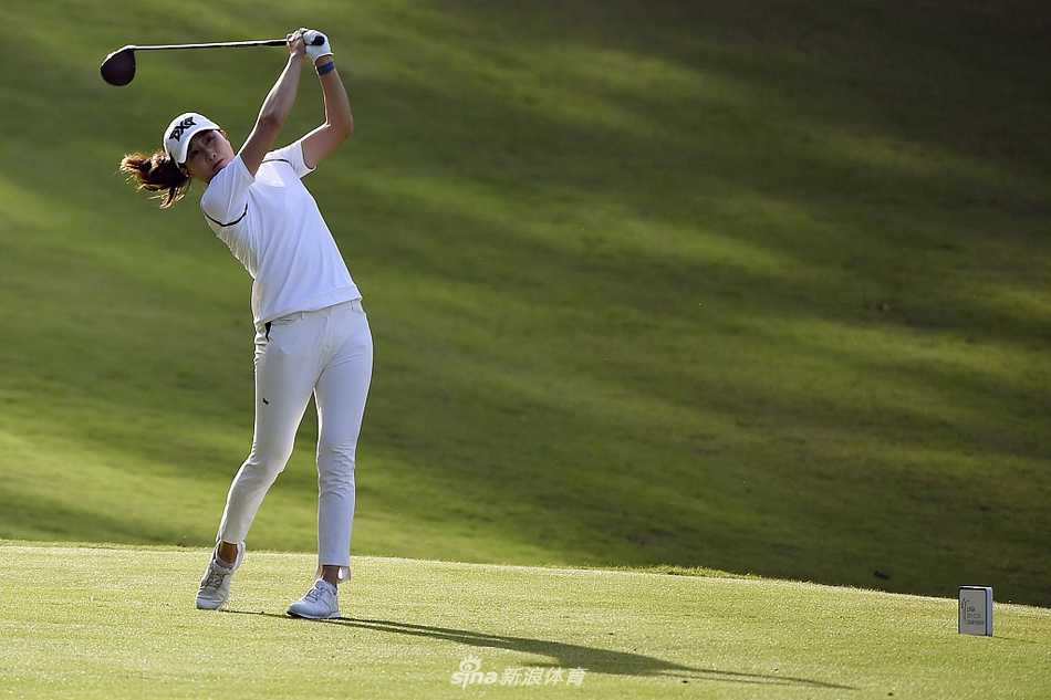 续航锦标赛首轮激战 姜孝林与詹妮弗宋并驾齐驱 詹妮弗·宋优雅完成推杆动作,小球滚向洞杯瞬间,背景是静谧的湖泊与树林。