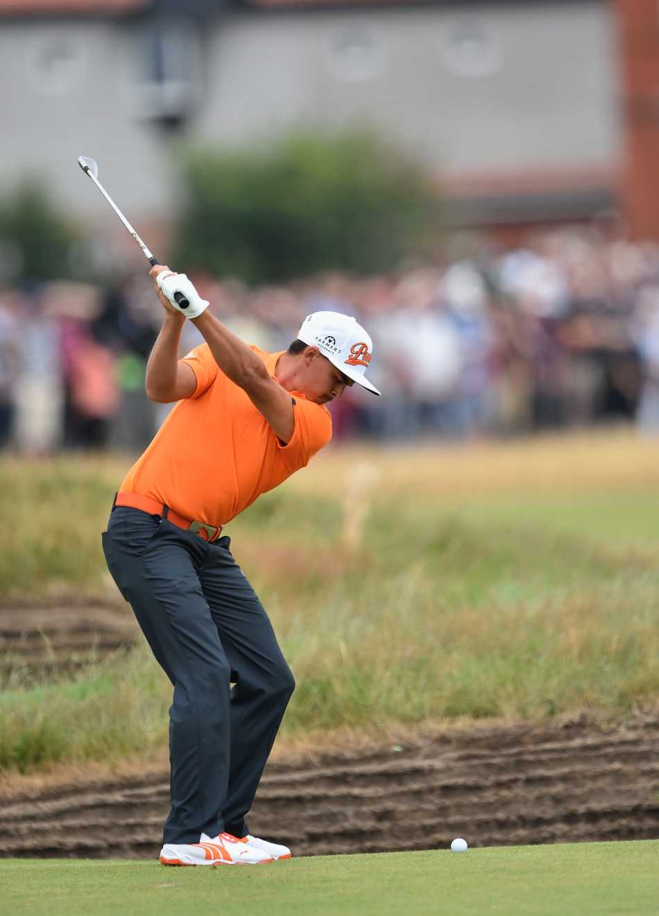 里奇福勒在沙坑边缘凝神救球，身体大幅度倾斜以寻找最佳击球点，展现出极限平衡能力