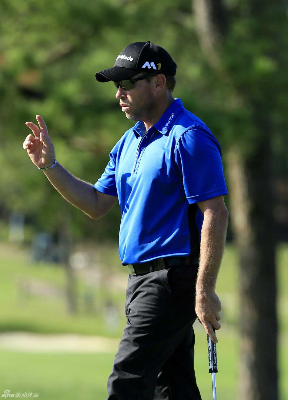 布赖恩·戴维斯正专注地进行推杆，他的姿势标准，眼神紧盯着球洞方向