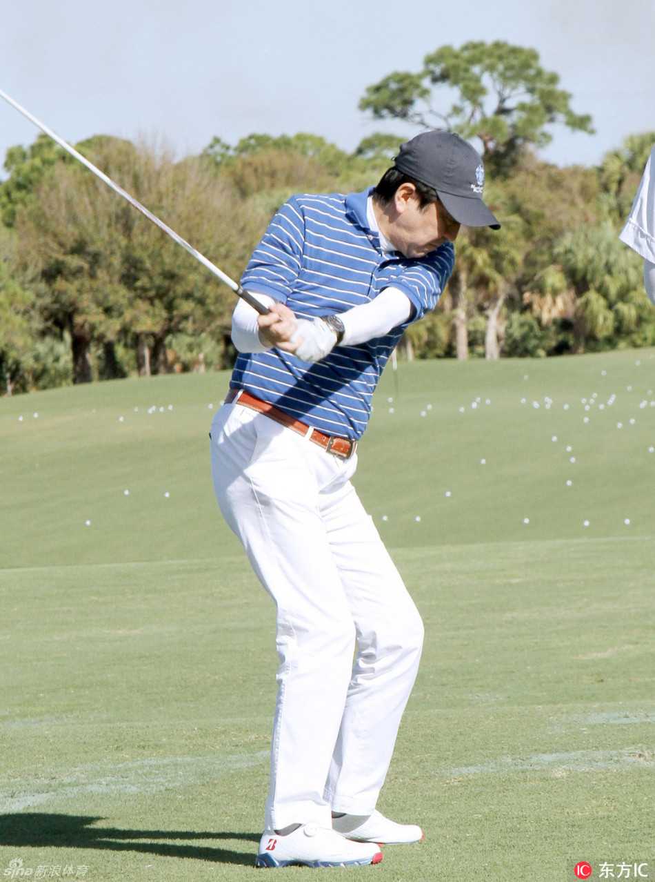 特朗普手握一支高尔夫球杆，似乎正在向镜头展示安倍首相赠送给他的特定品牌一号木