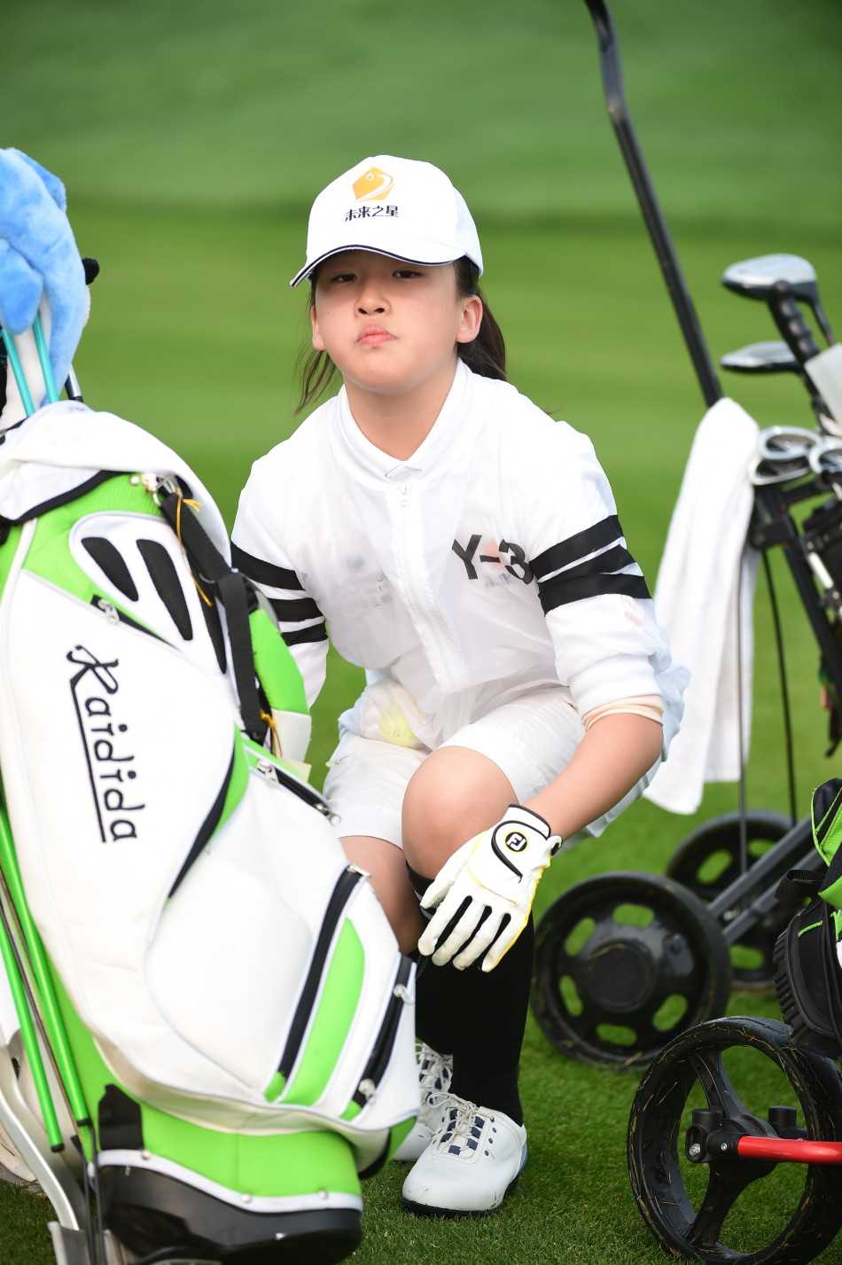 清晨微光中，扎着马尾辫的小女孩认真整理帽檐，目光坚定地望向远方赛场