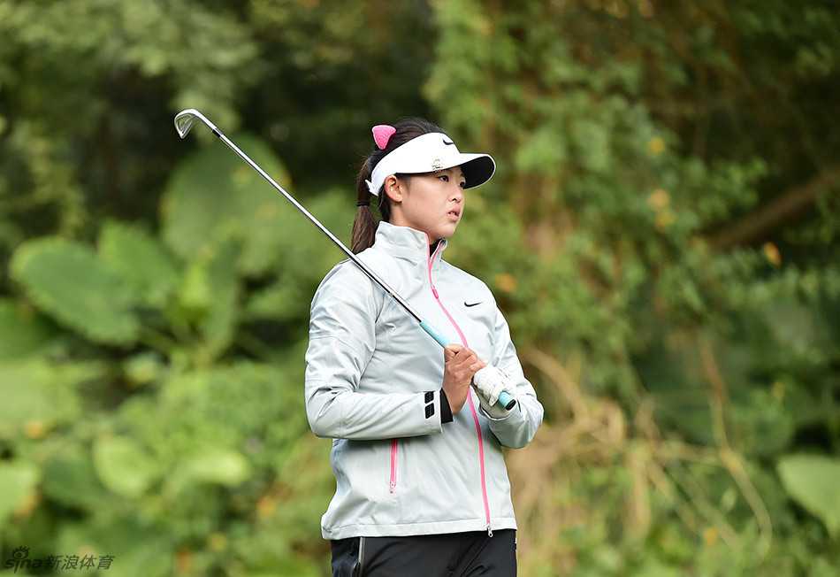 洪兰与球童并肩蹲在果岭边，低声交流，共同推敲最佳的击球方案。