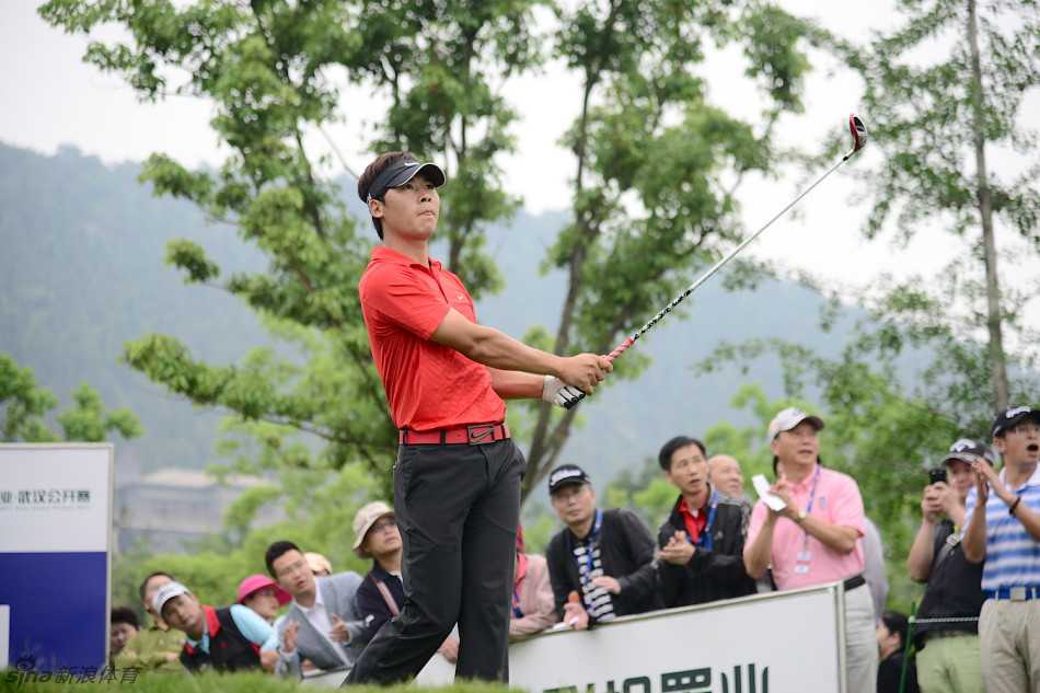 张新军背对镜头走下果岭，身影在午后阳光下显得沉稳而坚定，仿佛承载着一天的拼搏与故事。