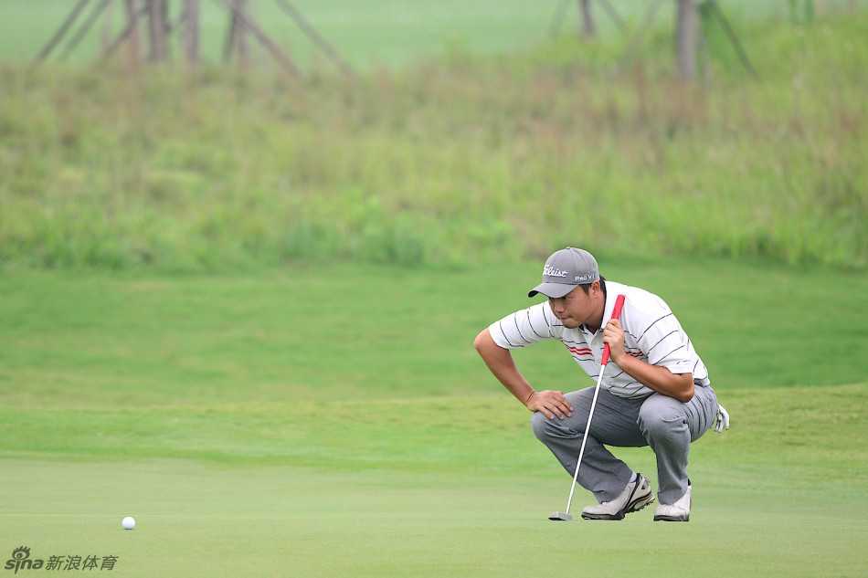 胡牧俯身仔细观察果岭上的草纹走向与坡度，全神贯注地研判推杆的线路。