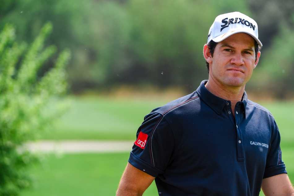 西班牙球手帕布罗-拉拉扎巴尔在果岭上俯身，用手指感受草皮纹理，为推杆做最后准备。