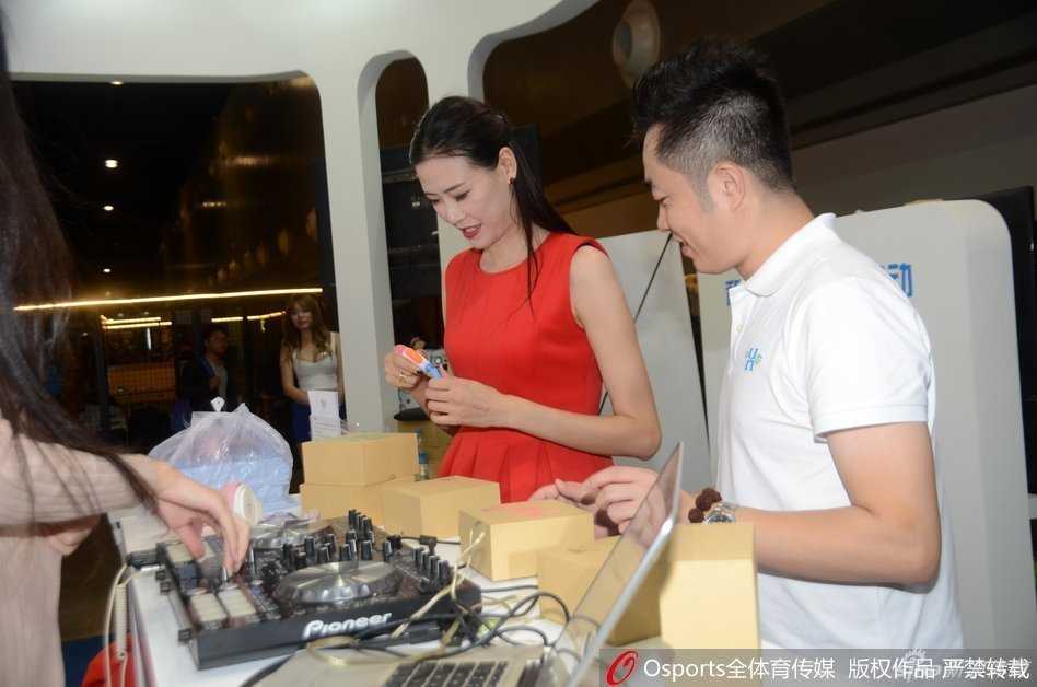 许诺身着一袭优雅的红色连衣裙，脚踩过膝长筒靴，在义卖现场带着温暖的笑容，正俯身为一位男粉丝在篮球上签名，1米95的身高让她在人群中显得格外突出。