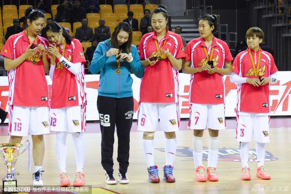 教练组成员在聚光灯下接过冠军戒指，脸上洋溢着满足的微笑，并与身边的弟子们分享着这份属于团队的荣誉。