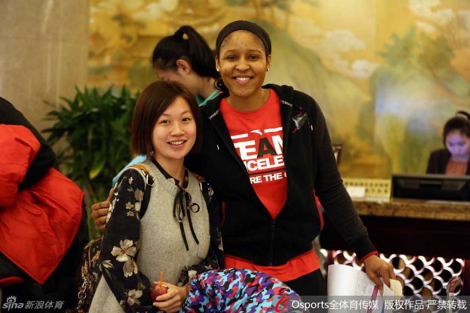 WNBA传奇球星玛雅-摩尔现身赛场边，面带温暖笑容满足球迷合影要求，毫无巨星架子
