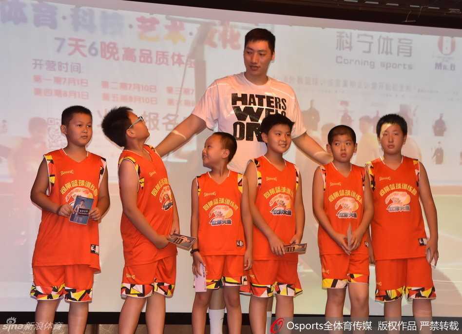 唐正东耐心地弯下腰，为面前一位可爱的小球迷在篮球上签下自己的名字，他脸上挂着温和的笑容，眼神中充满了对下一代篮球爱好者的鼓励与喜爱。