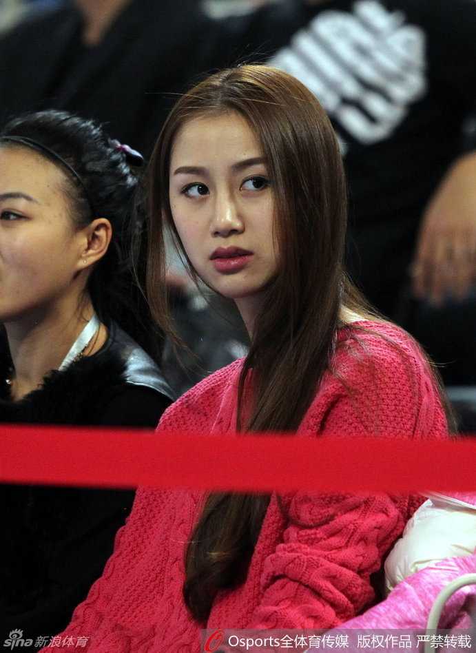 陈露与身旁的女性密友亲昵地靠在一起，两人低头私语，脸上露出默契的笑容，展现了她在场边极佳的观众席人缘