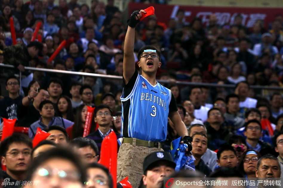 京疆决战夜的五棵松:球迷骚乱与卫冕冠军的悲情谢幕 光线昏暗的看台一角,几名球迷越过护栏闯入场地边缘的警戒区,他们背对镜头,目光齐齐投向远处还在理论的人群,现场只剩下混乱的脚步和嘈杂的人声。