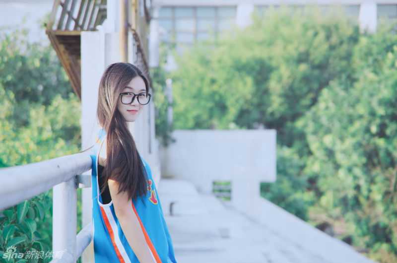 任丹妮侧身坐在篮球架下，手里轻轻旋转着篮球，修长的身材与球场线条构成一幅充满青春荷尔蒙的优美画面。