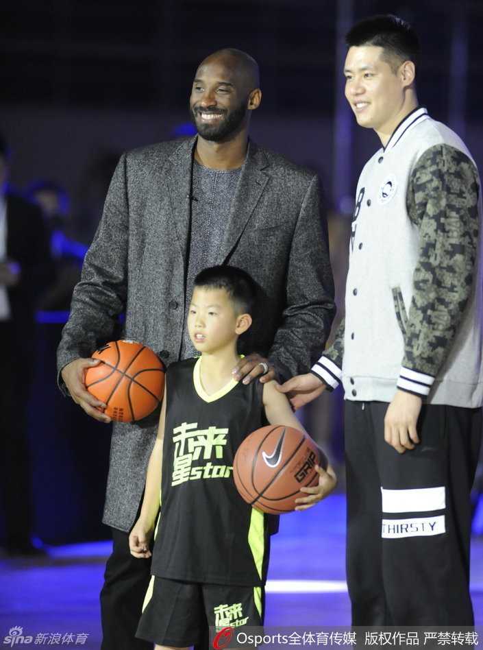 科比从嘉宾手中接过具有地方特色的纪念品，他面带微笑，这份礼物承载着沈阳球迷对他的深厚情谊。