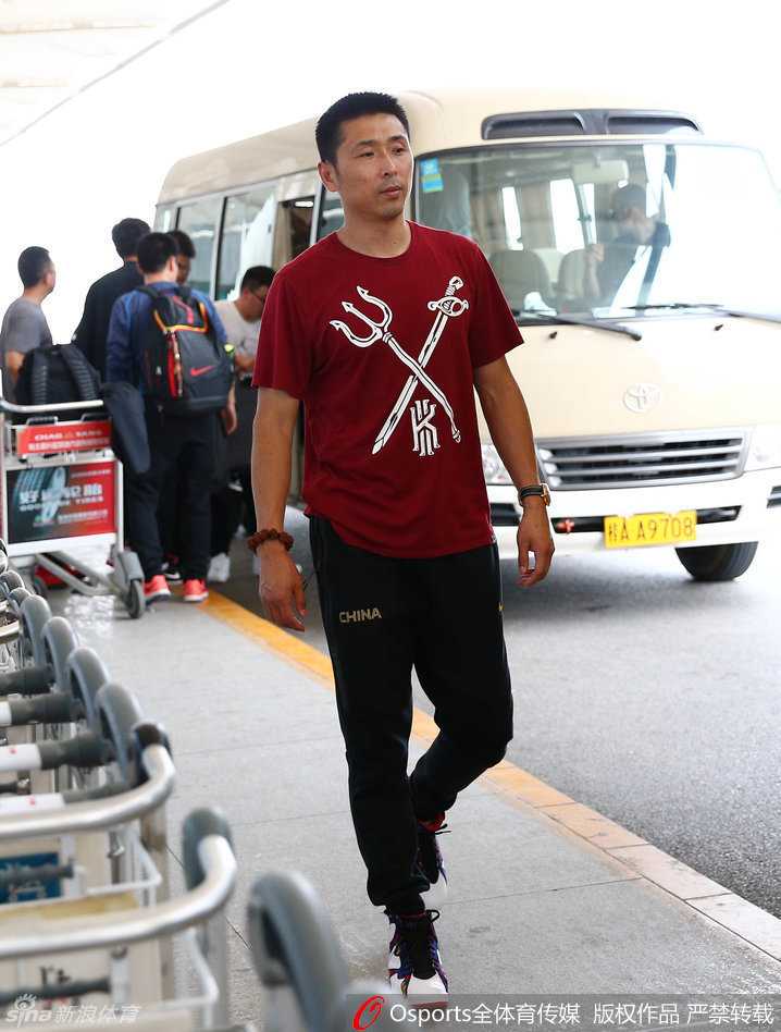 助教胡雪峰神情严肃地推行李车，他将后卫线的组织重任扛在肩上，悉心指导年轻队员。