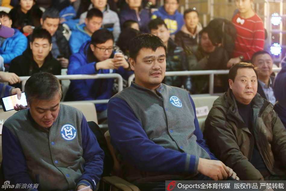 身高出众的姚明在场上执法时显得格外醒目，他正专注地盯着场上队员的一举一动，表情严肃又带着一丝笑意