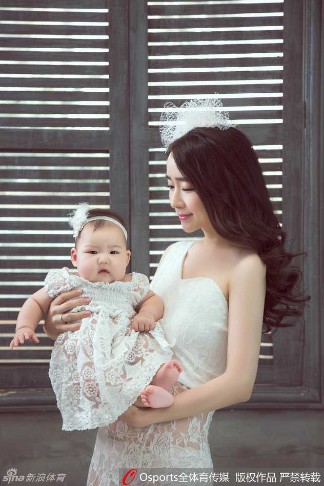 赵丹丹轻抚女儿的小手，眼神温柔似水，母女俩的亲密互动在镜头下显得格外唯美，辣妈的好身材在简约装扮下一览无余。