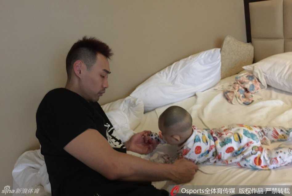 伊朗中锋哈达迪将小公主高高抱起，这位在篮下具有统治力的亚洲第一中锋，此刻化身为温柔的巨人。他怀抱着肉嘟嘟的小公主，眼神中透露出长辈的慈爱，仿佛在端详一件稀世珍宝，庞大的身躯与怀里的小不点形成了极具反差的温馨画面。