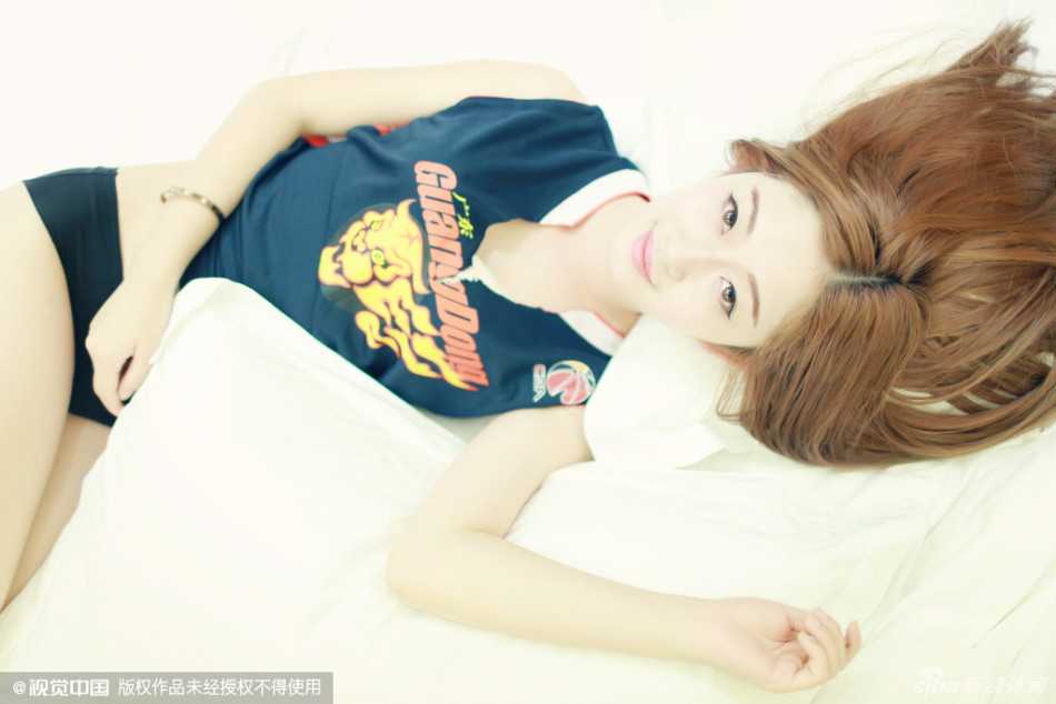 一位宏远宝贝侧卧在球场边线处，身穿闪钻紧身衣，右手轻托脸颊，眼神迷离而深邃，紧身衣上的亮片在灯光下熠熠生辉，宛如球场上的璀璨星辰