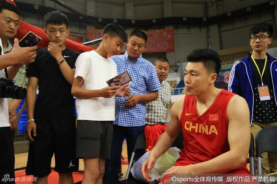 球迷热情索要签名，李根认真满足球迷愿望，身旁周鹏见状喜笑颜开，而郭艾伦则在一旁神游天外，表情茫然，形成鲜明对比。