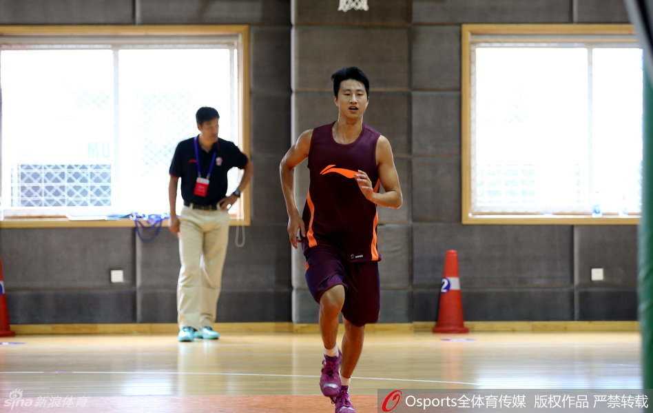 球场边上，完成测试的队员们有的在放松肌肉，有的在交流心得，身后的广告牌上写着体测相关的标语，整个球馆充满了紧张后的轻松氛围。