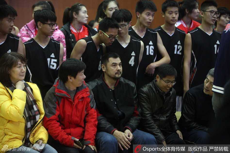 高大的女篮队员化身小老师，弯腰低头仔细聆听学生的问题，画面温馨而有爱