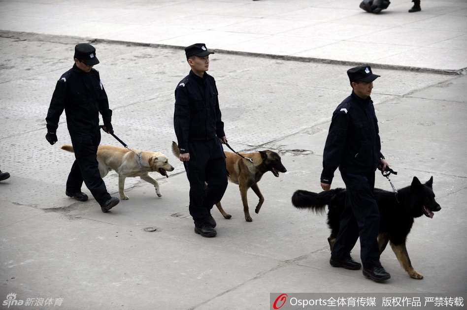 一辆巨大的水炮车静静停靠在体育馆外围的指定位置，巨大的轮胎和车身上的警示标志彰显着它的力量，它是维持场外秩序的终极后盾。