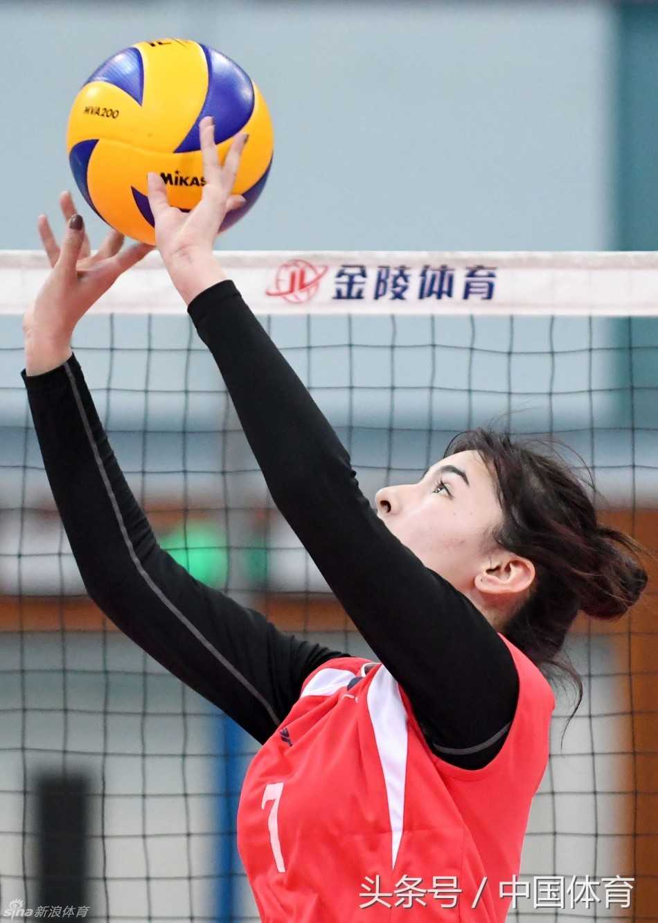 阿迪娜在发球区准备，她将球在手中转了转，深吸一口气，表情专注得仿佛整个世界只剩下眼前的这颗排球