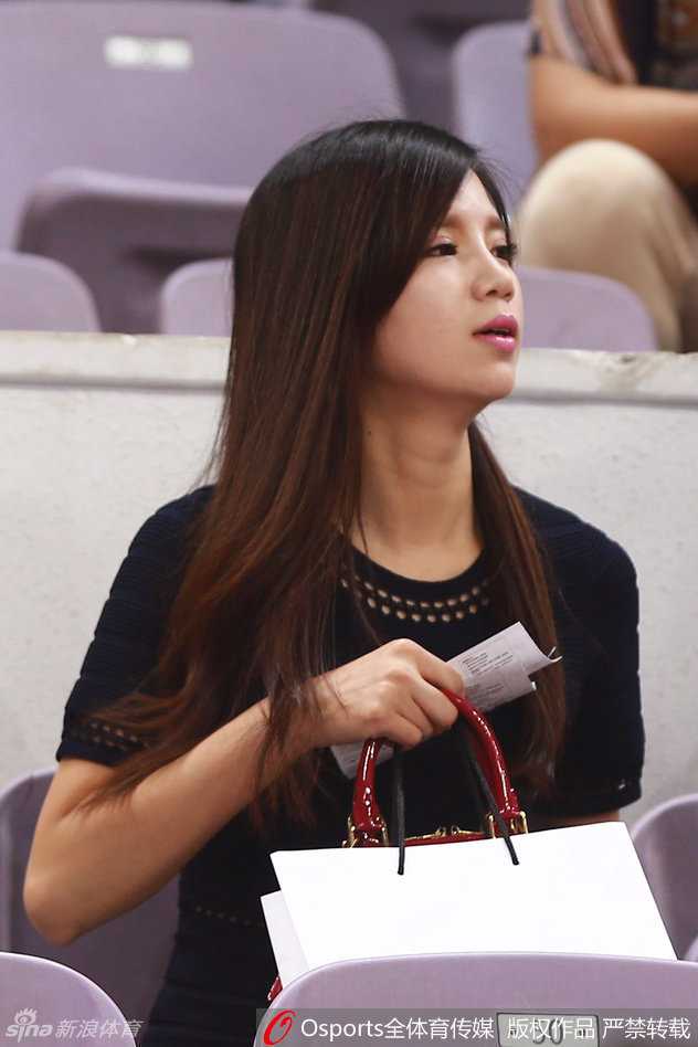 李根女友与友人凝视赛场，侧颜线条优美，眼神专注，美艳之中透着一丝紧张。
