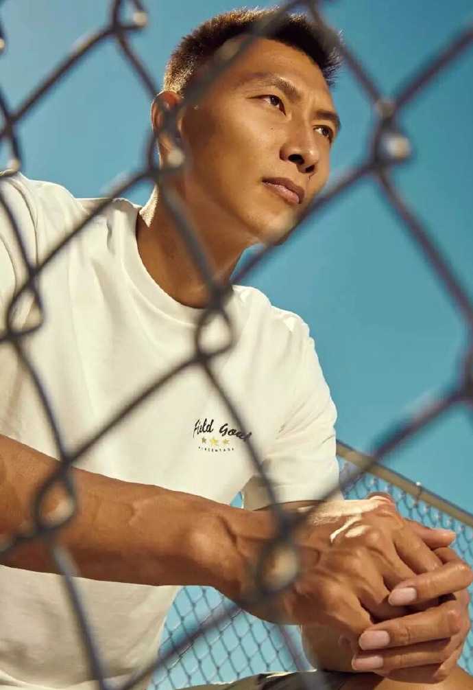 一个极具张力的特写镜头，易建联微微低头，眼神向上挑起，仿佛在审视猎物的雄鹰，脸部刚毅的线条在光影交错中显得格外立体。