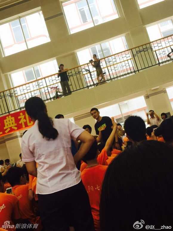 身穿笔挺衬衫的杨鸣，正在台上拿着话筒进行发言，他神情专注，眼神中透露出对篮球事业的坚定与热爱。